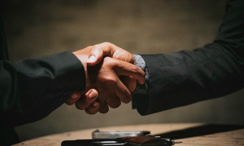 two people shaking hands over a wooden table